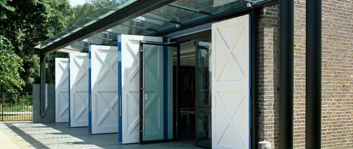 The Coach House Education Centre at Orleans House Gallery has a wall of glass doors and a glass canopy to maximise solar gain, with wooden doors that can be used to manage the amount of shading on warm days Photo Patel Taylor Architectural Practice